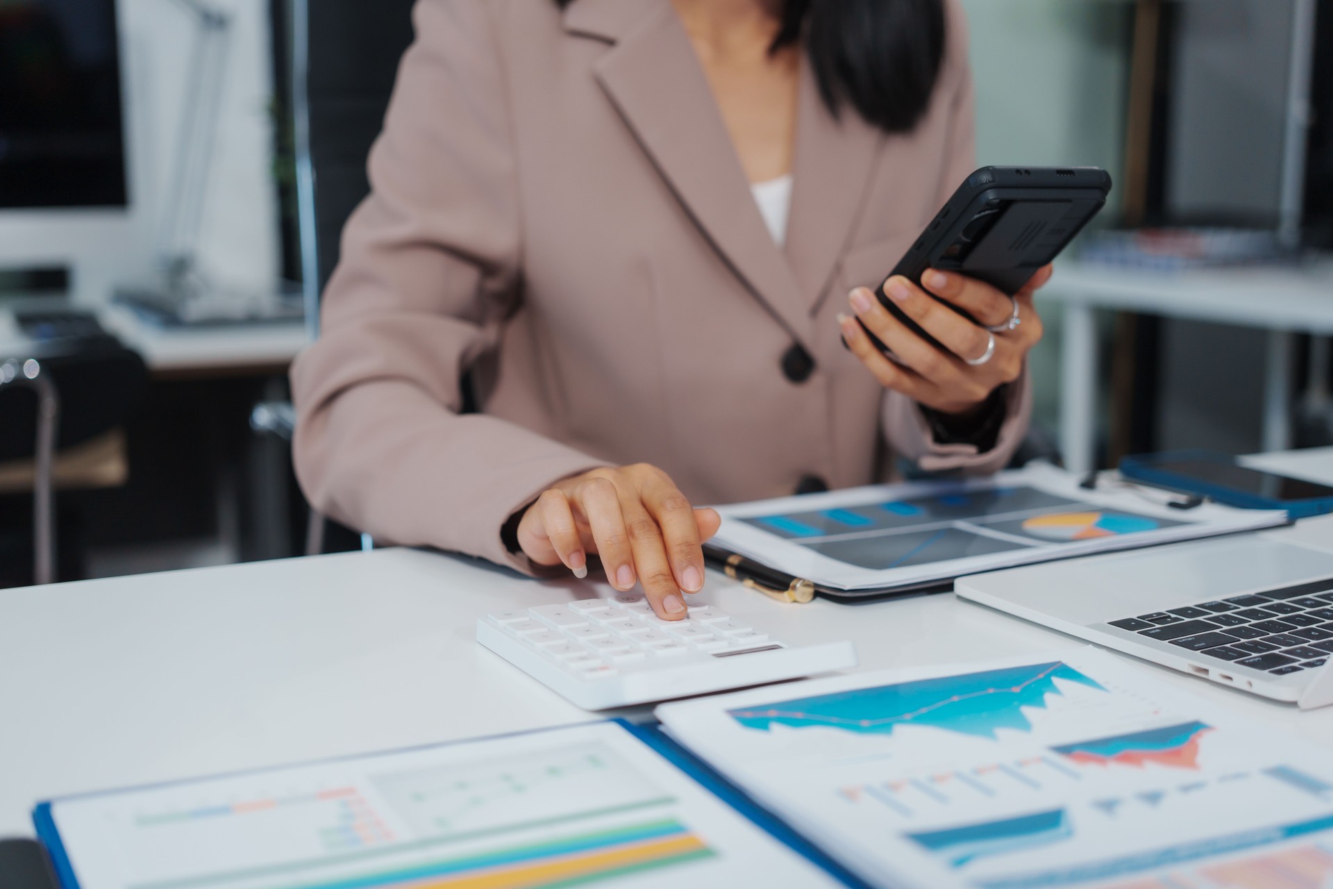 An Asian businesswoman accountant calculates invoices, taxes, interest, loans using a calculator,working online to guide clients through financial planning ensure a smooth loan process for success